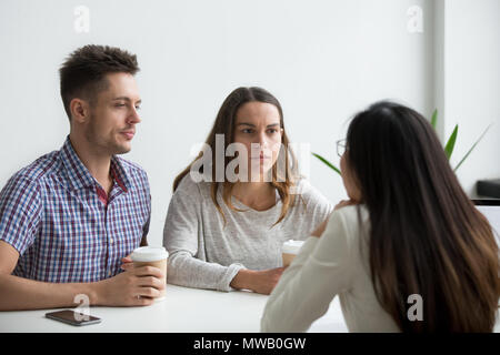 Doubtful distrustful couple suspicious listening to businesswoma Stock Photo