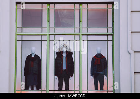 Three mannequins with clothes in storefront window closeup Stock Photo