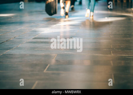 Blurred motion of peoples legs walking on pavement with copy space Stock Photo