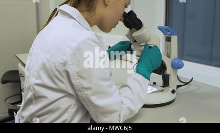 Doctor woman working a microscope. Female scientist looking through a microscope in lab. Student girl looking in a microscope, science laboratory concept Stock Photo