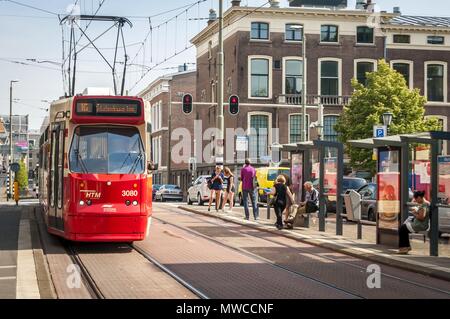 HAGUE (DEN HAAG), NETHERLANDS. July 19, 2017. Red city tram in the downtown Hague with passengers waiting for public transportation at the bus stop Stock Photo