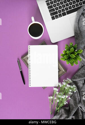 Home work space with notebook, laptop and coffee on pastel violet background. Home office flat lay top view. Stock Photo
