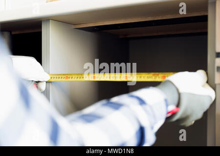 Home improvement and interior design concepts. Contractor taking measures of a brand new kitchen cabinet Stock Photo
