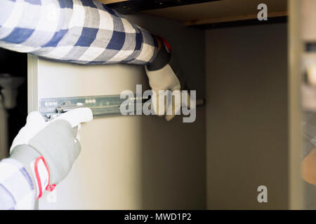 Home improvement and interior design concepts. Contractor adjusting kitchen cabinet shelf hinge Stock Photo