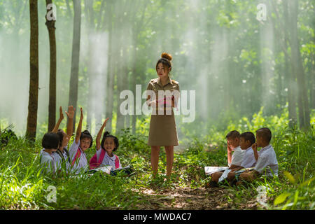 Sakonnakhon, Thailand - July 30, 2016: Beautiful teacher in uniform teaching her students outdoor class in forest public park in Sakonnakhon, Thailand Stock Photo