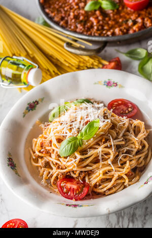 Spaghetti bolognese with ingredients basil tomatoesparmesan cheese and olive oil. Stock Photo