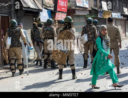 Kashmiri Muslim young girl walks past as Indian government force stands alert in Sinagar.Hundreds of people held peaceful protest soon after the congregational prayers at the Jamia Masjid (Grand mosque), in Srinagar. Heavy clashes broke out when the speedy central reserve paramilitary force’s (CRPF) vehicle allegedly hit two youths during protest in Srinagar. Stock Photo
