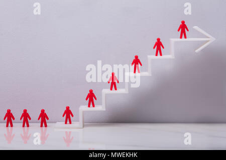 Red Human Figures Standing On Increasing White Arrow Graph In Front Grey Background Stock Photo