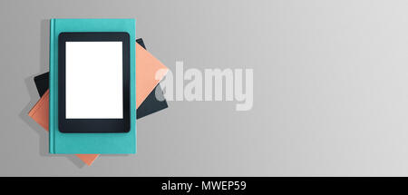 top view of e-book reader on stack of books on gray desktop Stock Photo