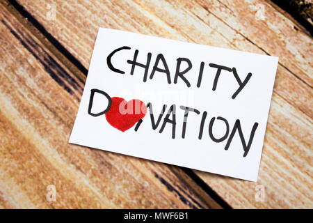 Conceptual image with Charity Donations handwritten message on the white paper with wooden background. Health and god will concept with red heart. Help for people having no money. Stock Photo