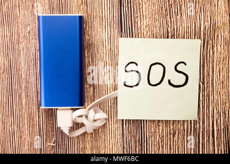 SOS handwritten word on white paper above retro wooden bark background. Concept with help sign on the white paper. Save our souls handwritten sign on the white paper. Stock Photo