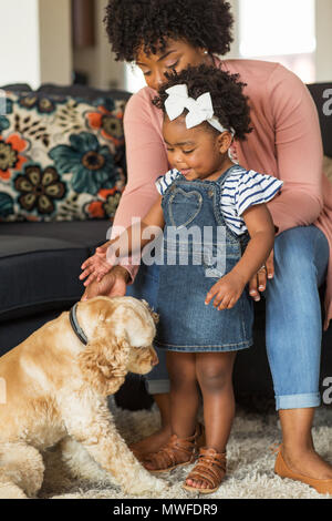 Little girl and her mom playing with thier dog. Stock Photo