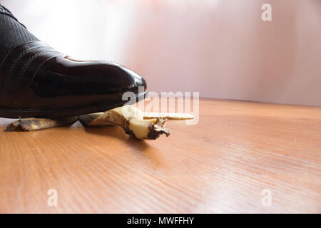 Black patent shoe of young man slipped on a banana peel. Stock Photo