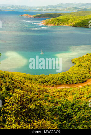 Sailboat anchoring in the bay below France's highest lighthouse at the Caravelle peninsula, Martinique, French Antilles Stock Photo