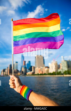 Colorful rainbow gay pride flag being waved in the breeze by a hand ...