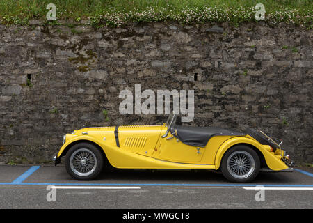 A vintage convertible car parked next to a stone wall in Europe Stock Photo