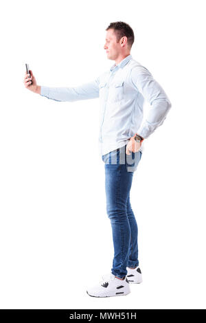 Profile view of elegant handsome business man taking photo with cellphone with hand on hip. Full body isolated on white background. Stock Photo