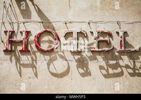 Hotel. Grungy advertising neon sign on an old building facade Stock Photo