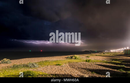 Dark black clouds with horizontal lightning as a thunder storm rages out at sea at night off the South Coast in the UK. Storm at sea. Stock Photo