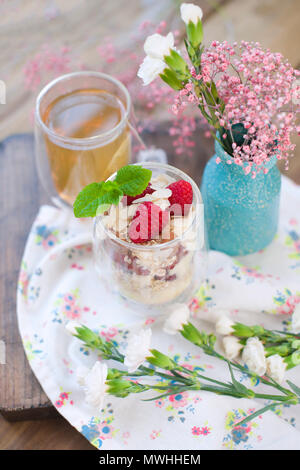 Tea in a glass and muesli, for breakfast on the table near the window, flowers and morning light. Stock Photo
