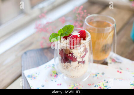 Tea in a glass and muesli, for breakfast on the table near the window, flowers and morning light. Copy space Stock Photo
