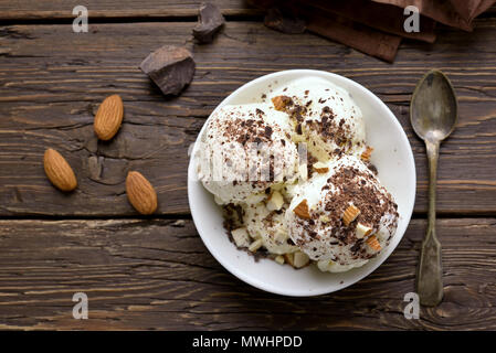 Vanilla ice cream with nuts in bowl on wooden background. Cold summer dessert. Top view, flat lay Stock Photo