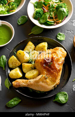 Tasty fried chicken leg with potato. Dish for dinner on black stone background. Top view Stock Photo