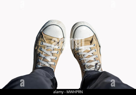 Feet in old khaki sneakers isolated on white background Stock Photo