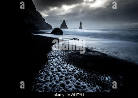 Reynisfjara is a famous, black sand beach near Vík í Mýrdal. But be careful, big waves may occur any time and have taken to many lifes. In the distanc Stock Photo