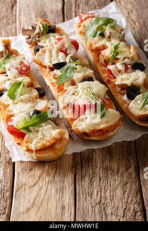 Delicious hot sandwich baguette baked with chicken, cheese, tomatoes, olives and mushrooms on the table. vertical Stock Photo