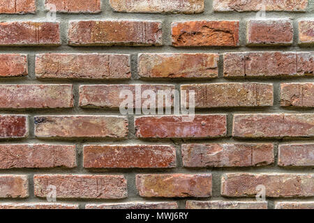 An old wall of restored bricks with a strongly faded red colour and uneven joints, germany Stock Photo