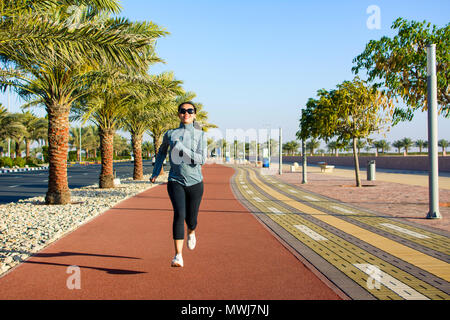 Girl jogging on the running track by the seaside Stock Photo