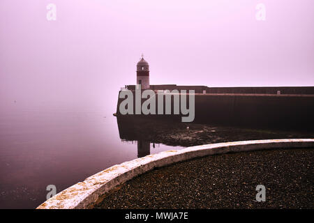 The outer harbour and lighthouse of Castletown in the Isle of Man early on a misty morning Stock Photo