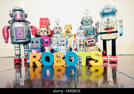 the word  robots with wooden letters and retro toy robots  on an old wooden floor with reflection Stock Photo