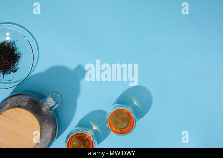 top view of fresh tea in cups and teapot and dry herbal tea on blue Stock Photo