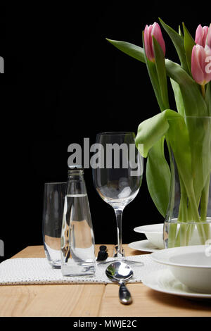 Vase with flower bouquet on table with festive tableware Stock Photo