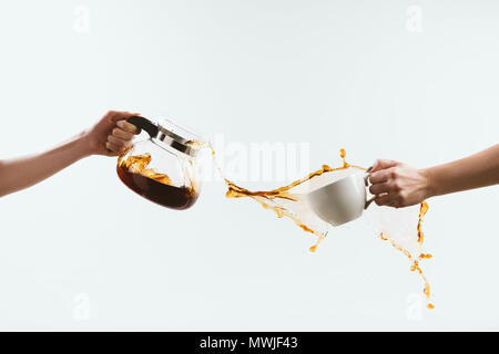 cropped view of person holding cup and glass pot with splashes of coffee, isolated on white Stock Photo