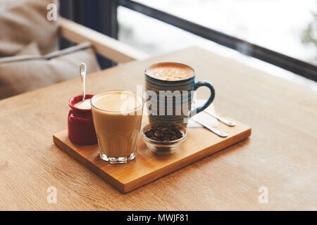 Coffee drinks with beans and orange peel on table in cafe Stock Photo