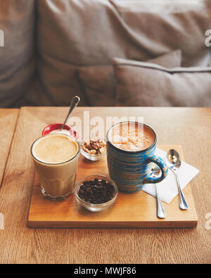 Hot coffee drinks in glass and cup with beans and nuts Stock Photo