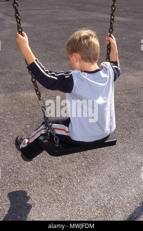 Six year old boy on a swing (rear view) Stock Photo