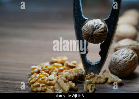 Whole walnuts, kernel walnuts and nutcracker on dark walnut table background Stock Photo