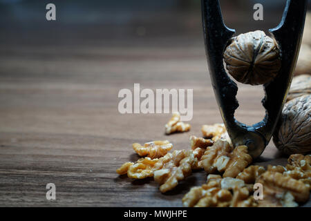 Whole walnuts, kernel walnuts and nutcracker on dark walnut table background Stock Photo