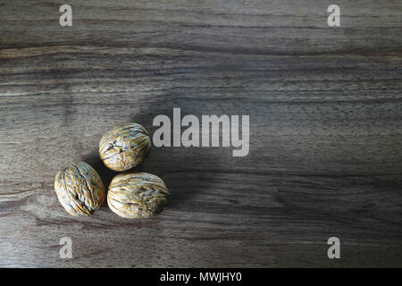 Top view of three walnuts on dark walnut table background Stock Photo