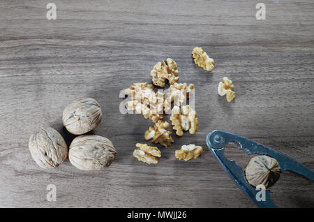 Top view of whole walnuts, kernel walnuts and nutcracker on dark walnut table background Stock Photo