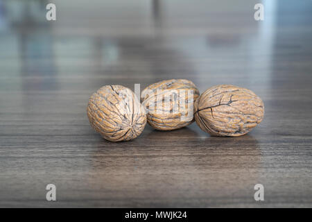 Three walnuts on dark walnut table background Stock Photo