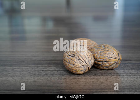 Three walnuts on dark walnut table background Stock Photo