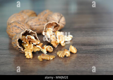Kernel walnuts in nutshells with whole walnuts on dark walnut table background Stock Photo