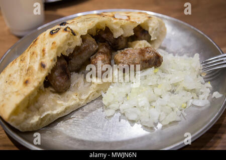 Cevapcici, Bosnian street food, cevapi in Sarajevo with onion and somun bread. Stock Photo