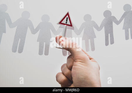 The boss gives a warning to the employee. Man warns another person from the crowd of people. Warning yellow card. Hand holding a sign with an exclamat Stock Photo