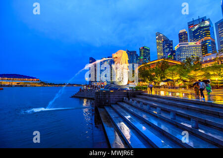 Singapore - April 27, 2018: Merlion Statue in Merlion Park with Central Business District or CBD Buildings illuminated in Marina Bay Harbor and waterfront. Scenic Singapore icon at blue hour. Stock Photo